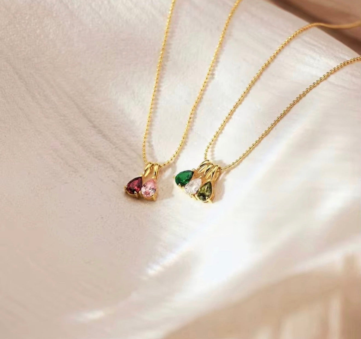 Birthstone necklaces with colorful stones on a soft neutral background