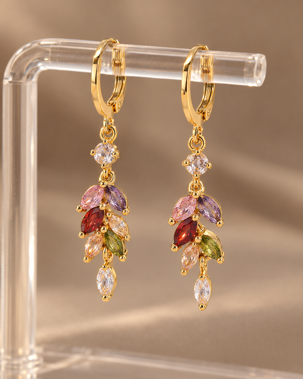 Pair of gold-tone multicolor zircon drop earrings on warm background