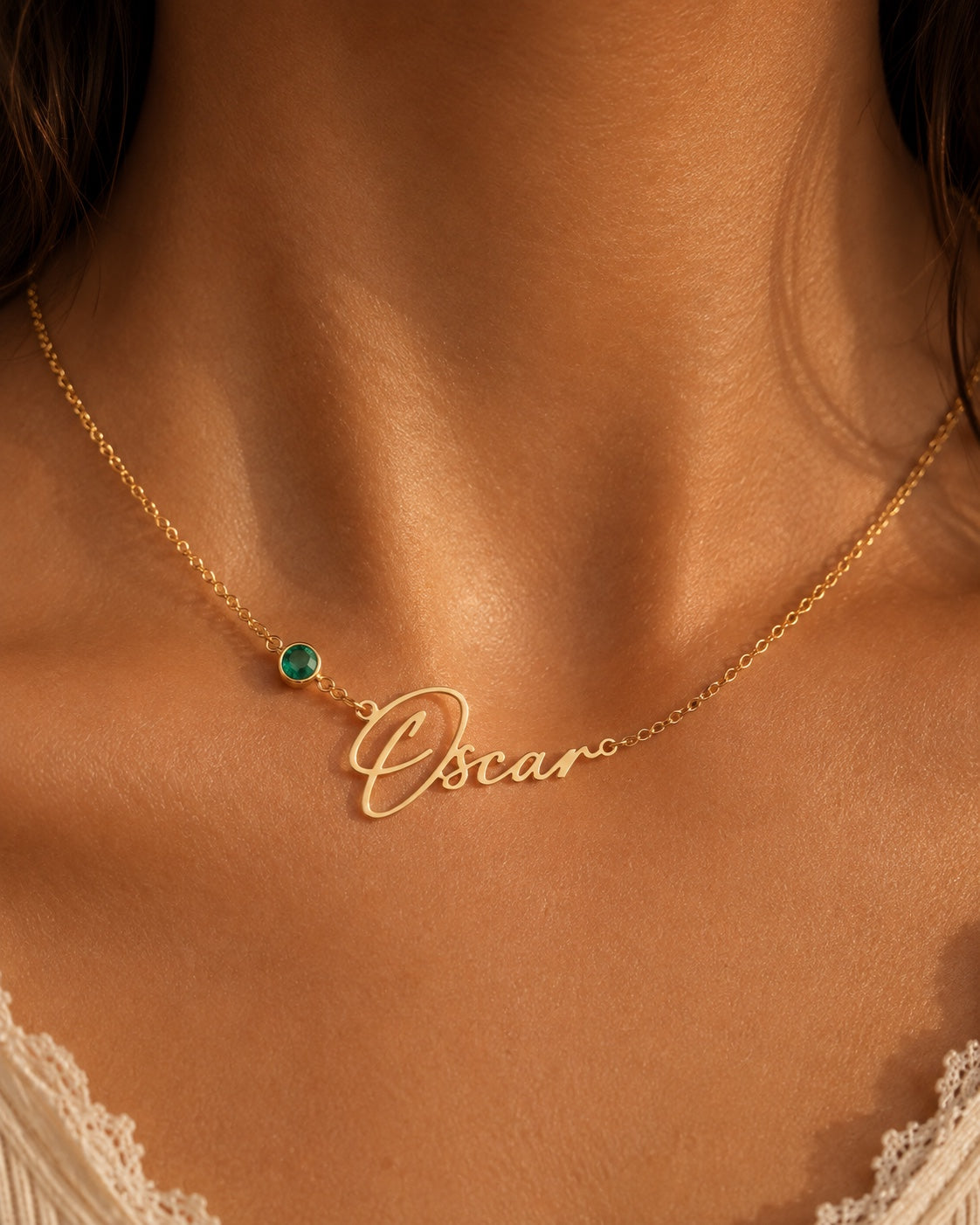 Close-up personalized gold name necklace with green birthstone
