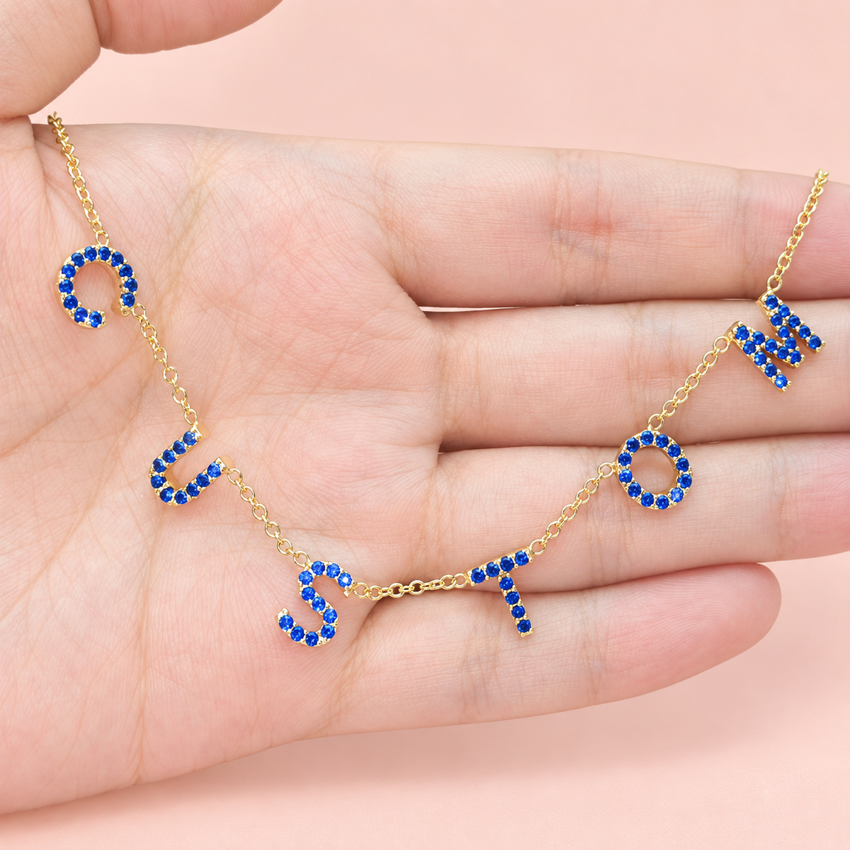 Collier personnalisé à lettres serties bleu profond sur main