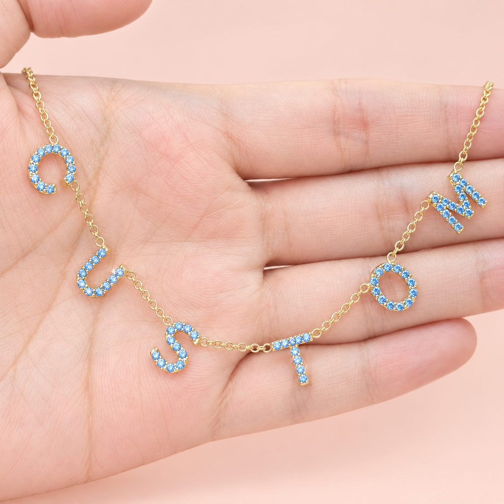 Collier personnalisé à lettres serties bleu ciel sur main