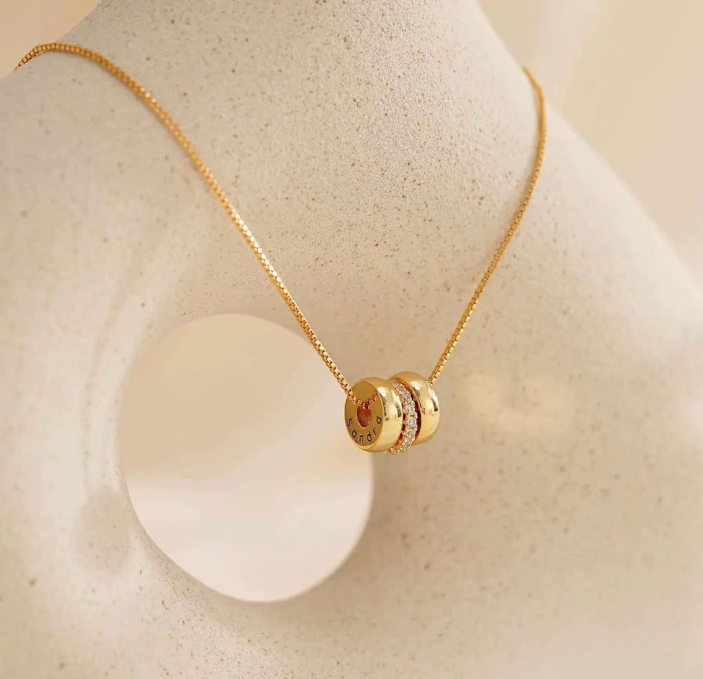 The Lyra gold personalized engraved name bead necklace on jewelry display