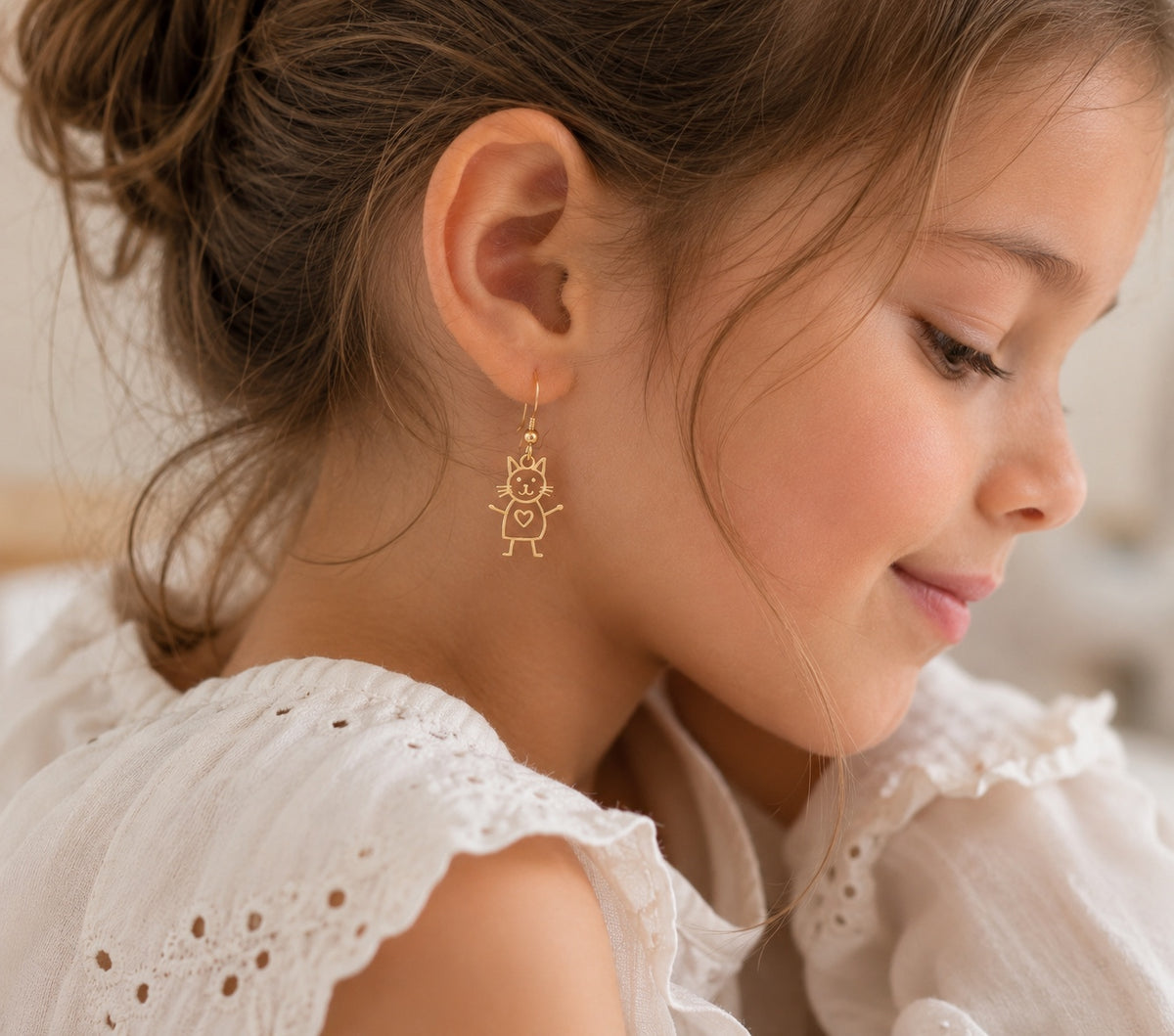 Child wearing personalized gold cat earrings from original artwork