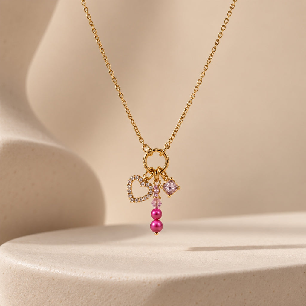 The Rosalie pink heart charm necklace on warm neutral studio background