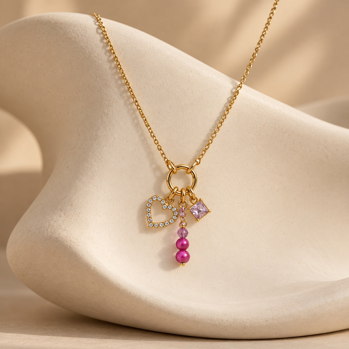 The Rosalie charm necklace displayed on sculptural cream jewelry stand