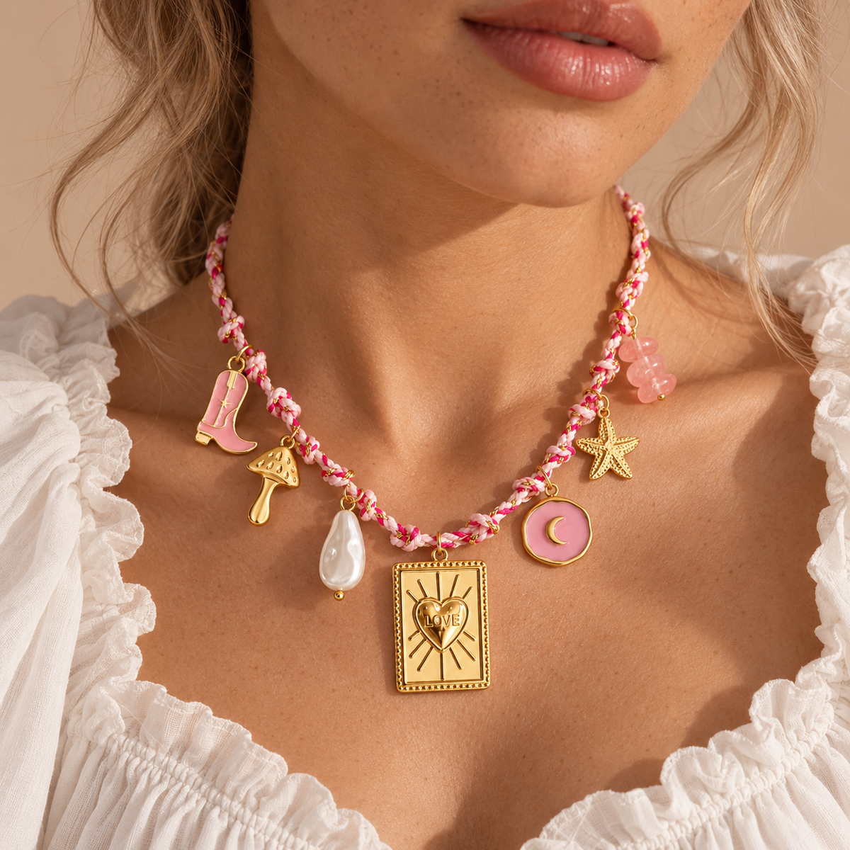 Pink and gold LOVE charm necklace on neutral studio background