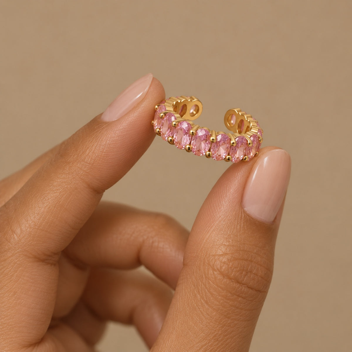 Gemline pink adjustable gold ring held between fingers